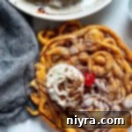 funnel cake with cherry and whipped cream drizzled with chocolate sauce