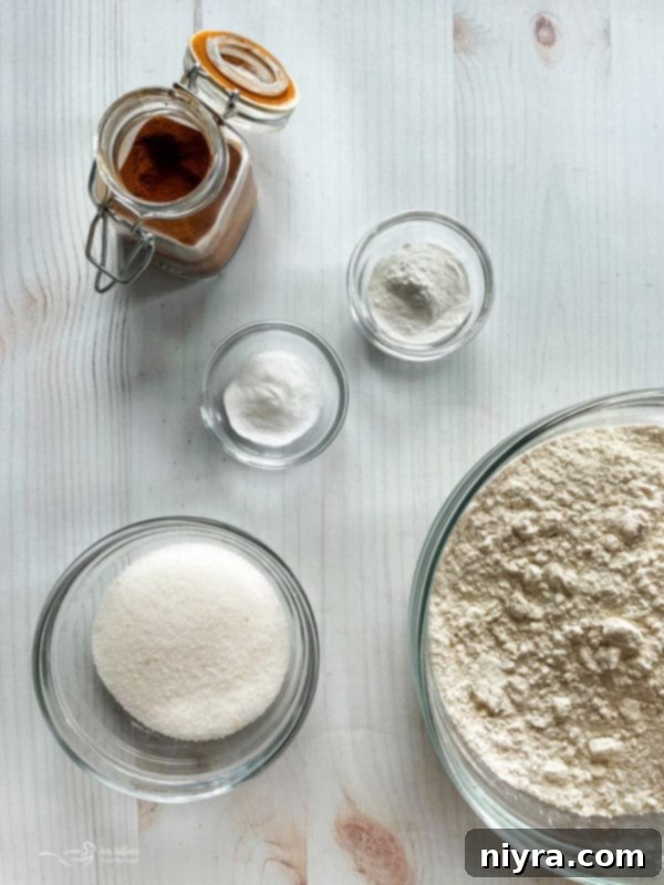 A collection of funnel cake ingredients including maple syrup, dry flour mixture, and sugar, arranged on a rustic wooden surface.