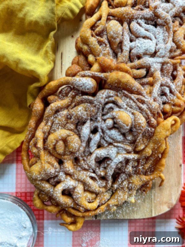 Several golden-brown homemade funnel cakes artfully arranged on a rustic wooden board, ready for toppings.
