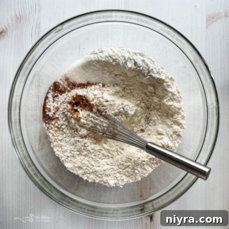A bowl containing a mixture of dry ingredients including flour and cinnamon, ready for the wet ingredients to be added.