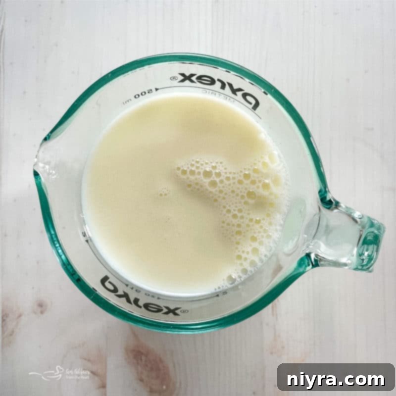 A single glass of milk, a key wet ingredient, stands ready for the funnel cake batter.