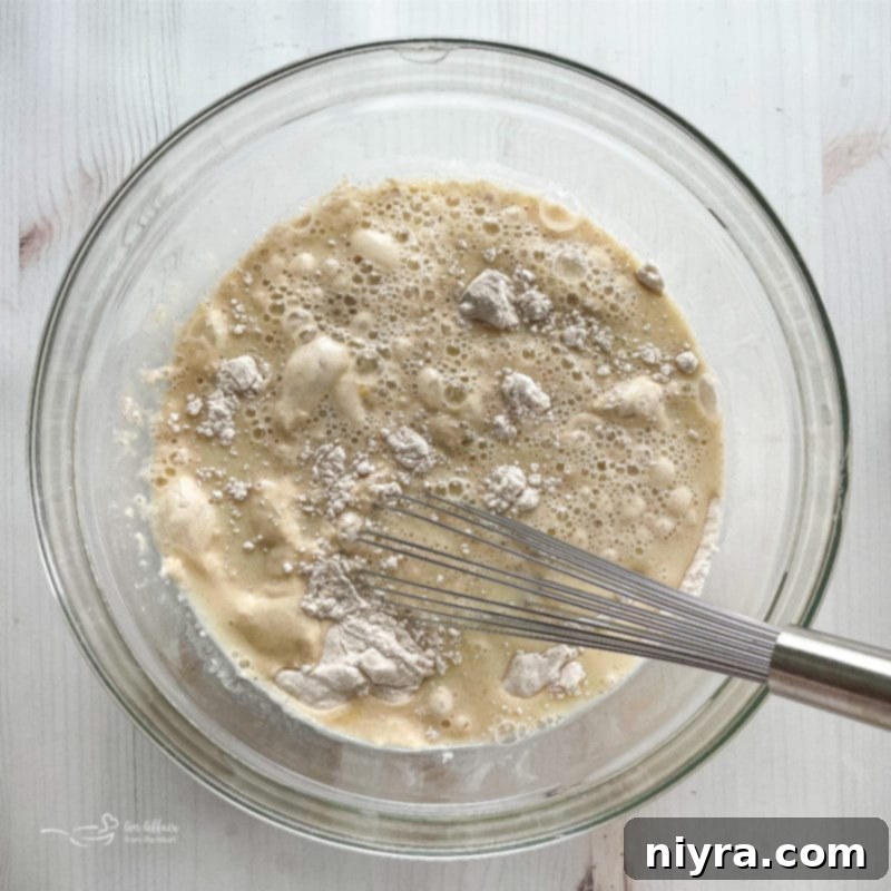 A glass bowl showcasing the perfectly smooth funnel cake batter, a blend of dry and wet ingredients.