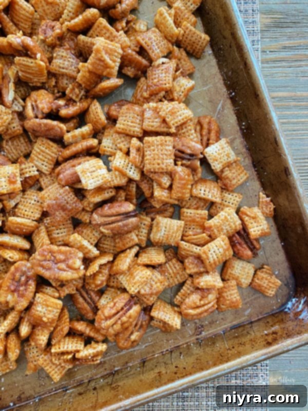 Top-down view of caramel pecan clusters baking on a sheet pan, showing their developing golden-brown color and crunchy texture.