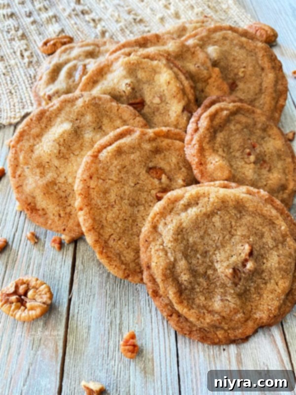 A charming group of golden-brown pecan butter cookies artfully arranged on a rustic wooden table, with whole pecans scattered nearby, suggesting their key ingredient.