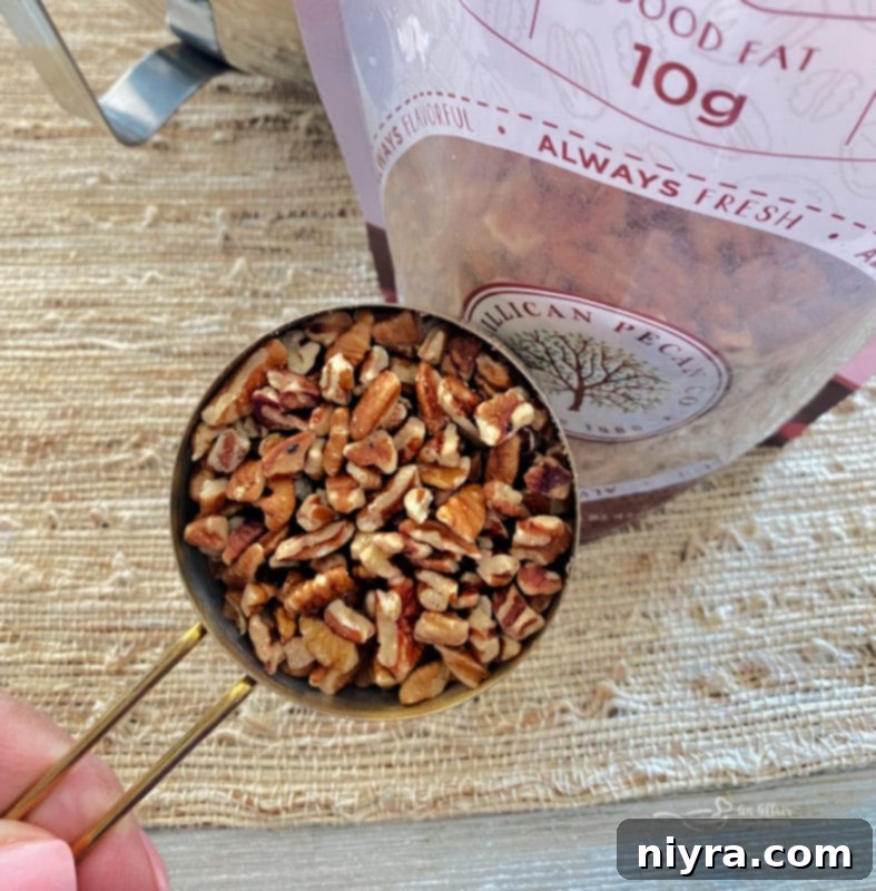 A measuring cup filled to the brim with whole pecans, showcasing their rich color and inviting texture, ready to be chopped and incorporated into the cookie dough.