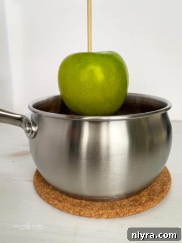 Dipping a Granny Smith apple into warm caramel