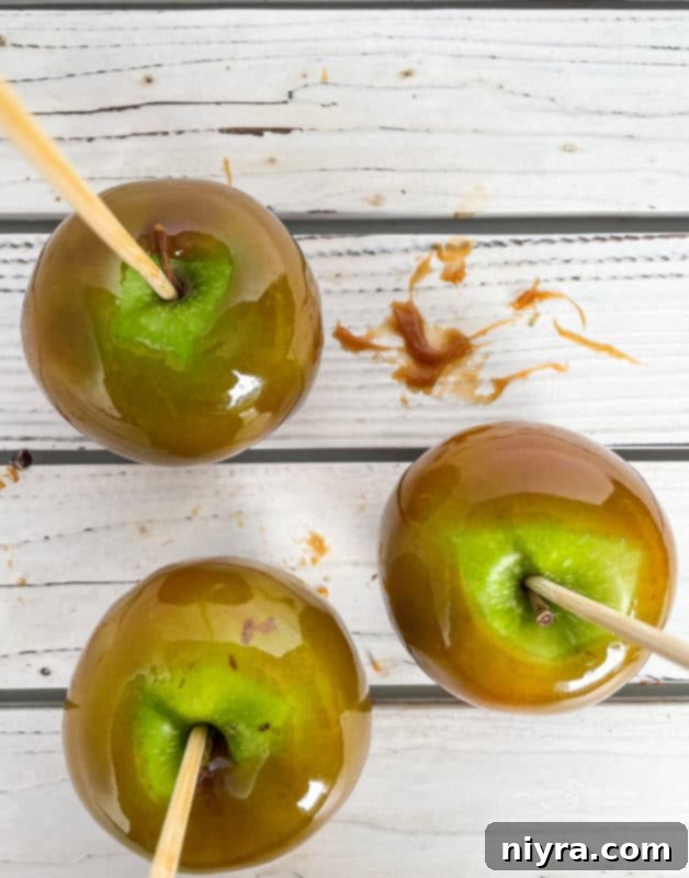 Caramel apple being rolled in chopped nuts