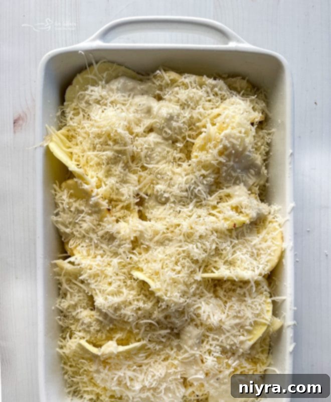 top view of potatoes and cheese being layered in baking dish