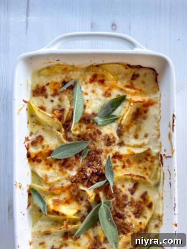 Cheesy Potatoes Au Gratin top view of potatoes au gratin in baking dish with bacon and sage leaves