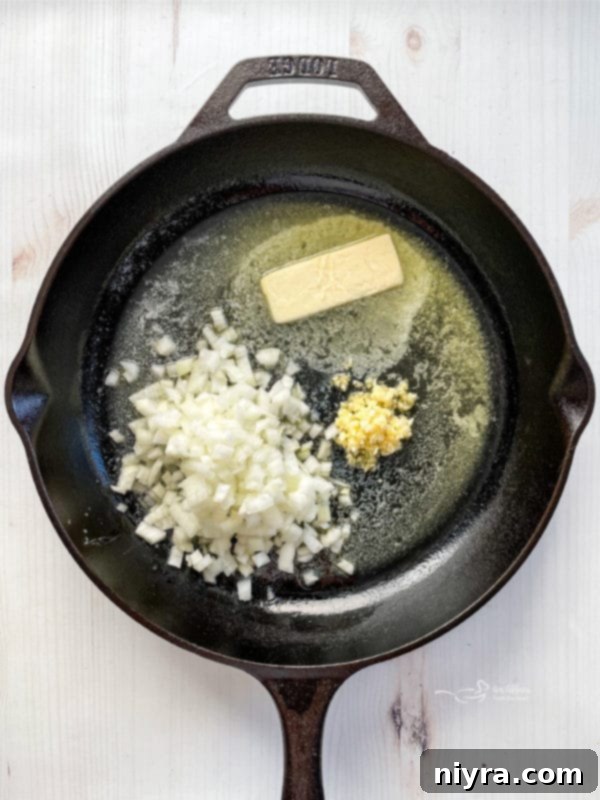 The Best Potatoes Au Gratin (Cheesy) melting butter in skillet with onion and garlic