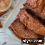 One loaf of applesauce bread on white plate with applesauce in bowl