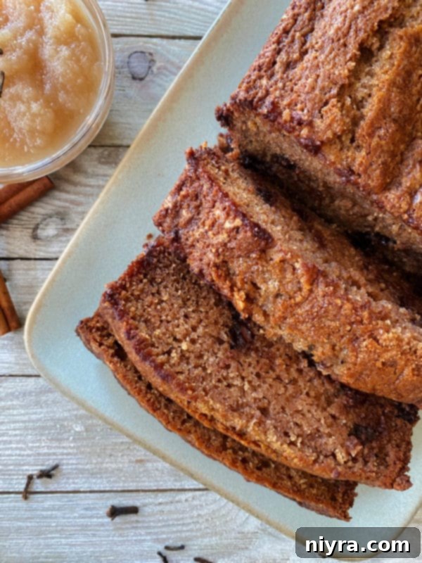 A single loaf of applesauce bread, perfectly baked and sliced into three inviting pieces, resting on a white plate, ready to be served.