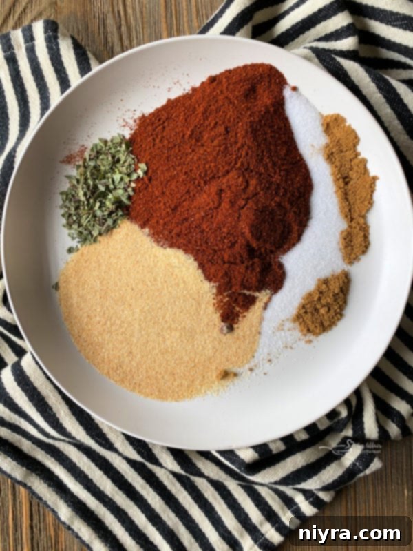 Close up of a bowl of red enchilada sauce with spices around it