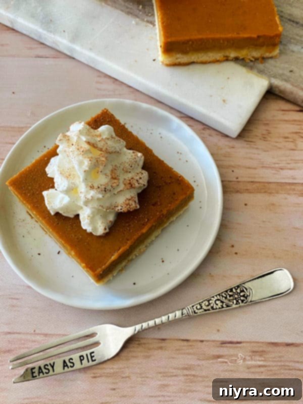 Buttery Shortbread Pumpkin Bars 2 Delicious Pumpkin Pie Bars with a Golden Shortbread Crust, topped with whipped cream and a sprinkle of cinnamon, ready to be served from a 9x13 baking dish.