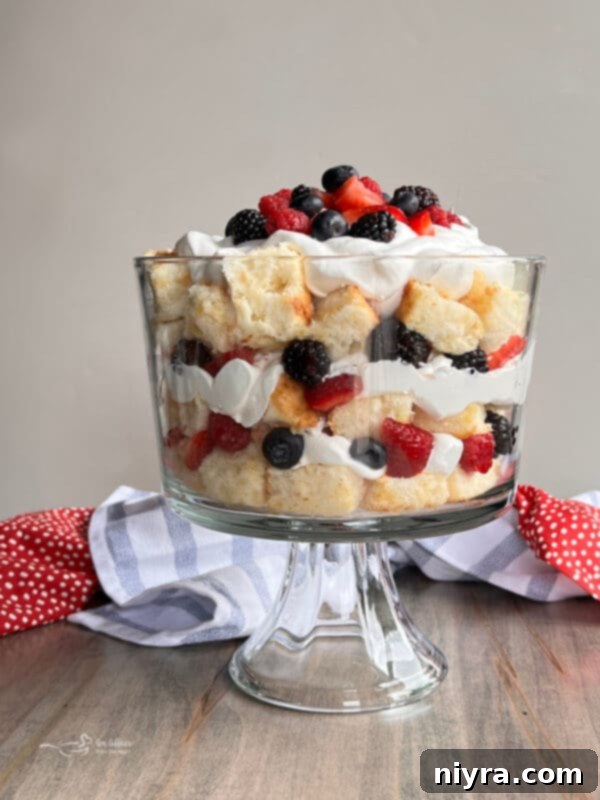 A beautifully layered Triple Berry Trifle in a glass bowl, showcasing fresh berries, whipped cream, and angel food cake