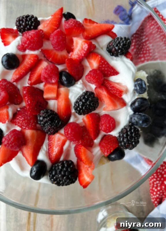 Adding fresh berries as the third layer in a Berry Trifle