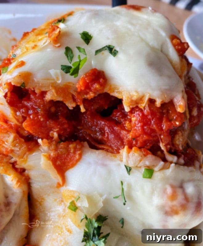 close view of chicken parmesan with cheese and tomato sauce, garnished with basil