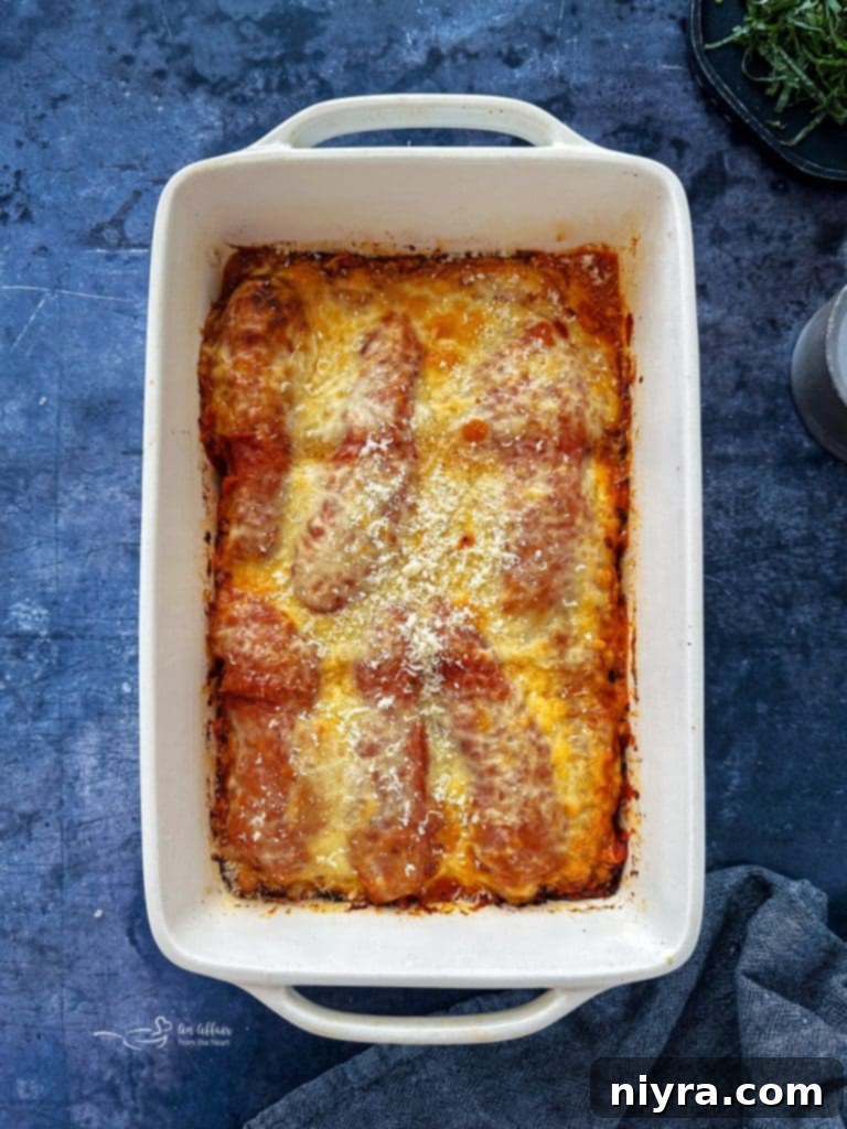 Mozzarella cheese slices on top of chicken and sauce in a baking dish