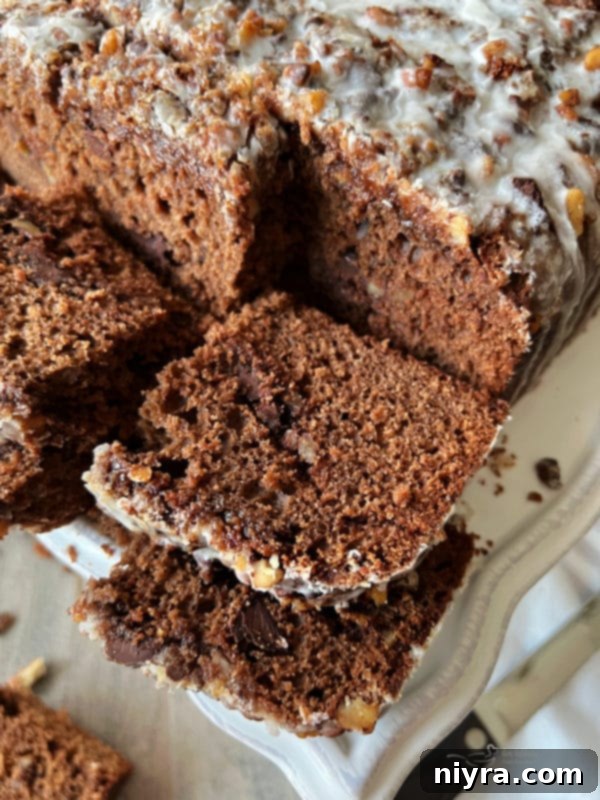 Bittersweet Chocolate Coffee Cake with glaze and streusel on a white plate with a fork.
