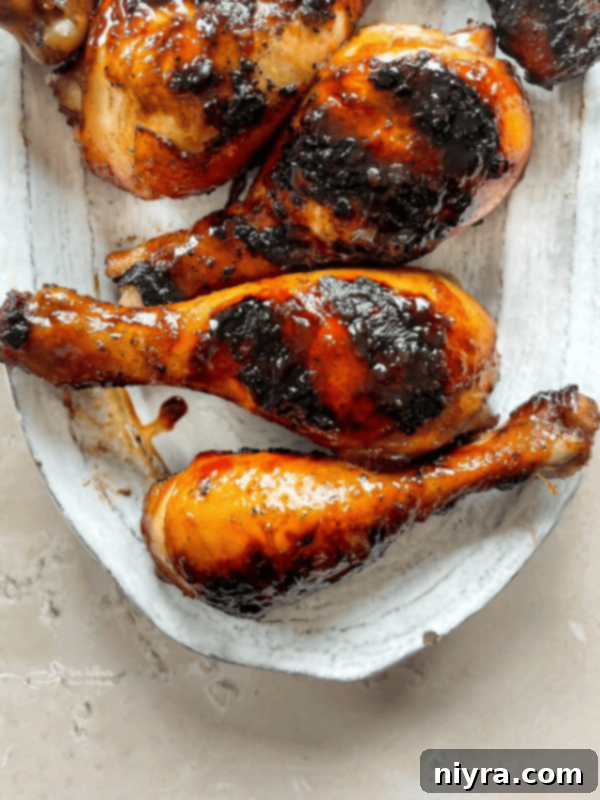 Sweet and sticky grilled chicken legs on a white plate with lemon