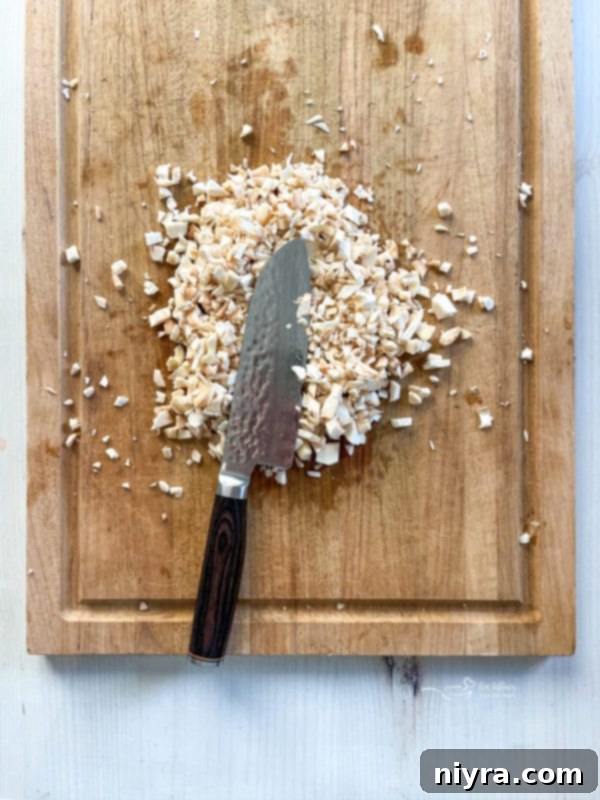 Finely chopped mushroom stems on a cutting board, ready for sautéing.