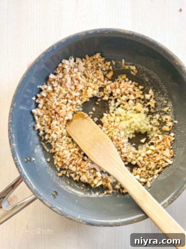 Mushroom stems and diced onion sautéing in a pan with butter.