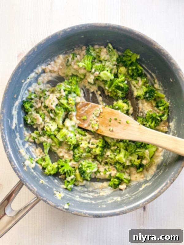Broccoli and flour being added to the sautéed mushrooms and onion in a pan.