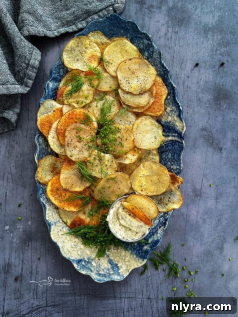Homemade baked potato chips in a bowl with a hand reaching for one