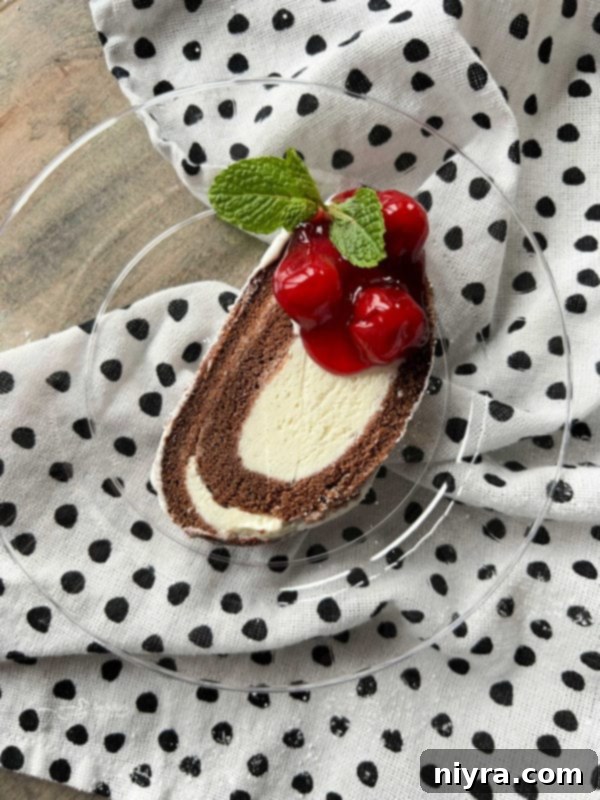 sweet piece of ice cream roll cake with cherry pie filling on top, garnished with fresh mint