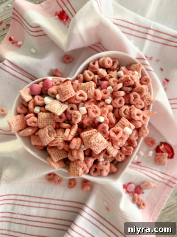 A bowl of White Chocolate Strawberry Muddy Buddies, a festive and sweet snack.