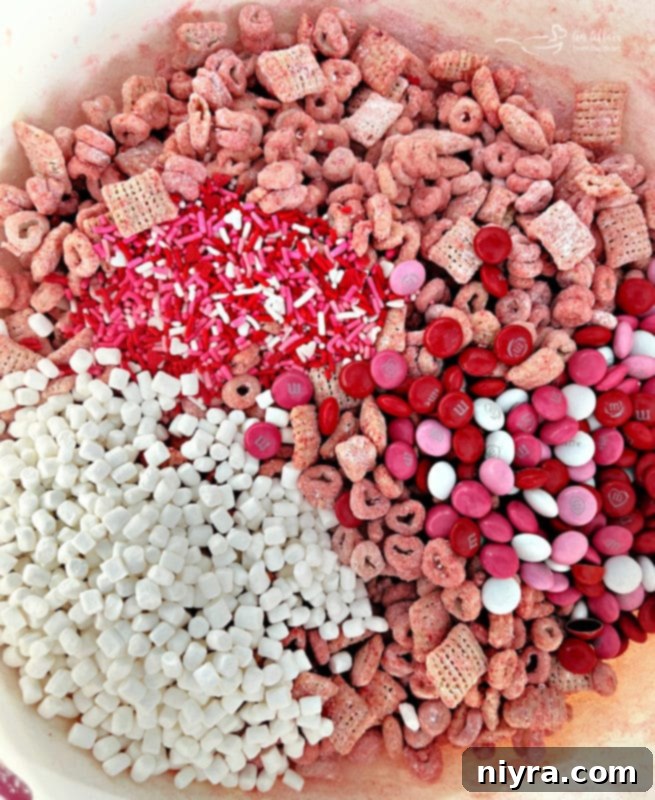 Cereal, M&M's, mallow bits, and sprinkles for pink Valentine's Day puppy chow on a surface.