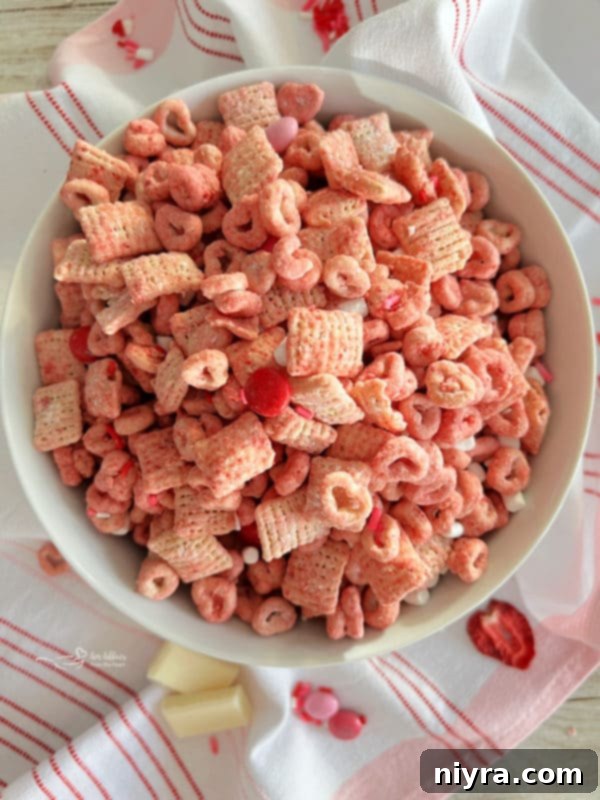 A large bowl of vibrant pink White Chocolate Strawberry Muddy Buddies, ready to be enjoyed as a snack or dessert.