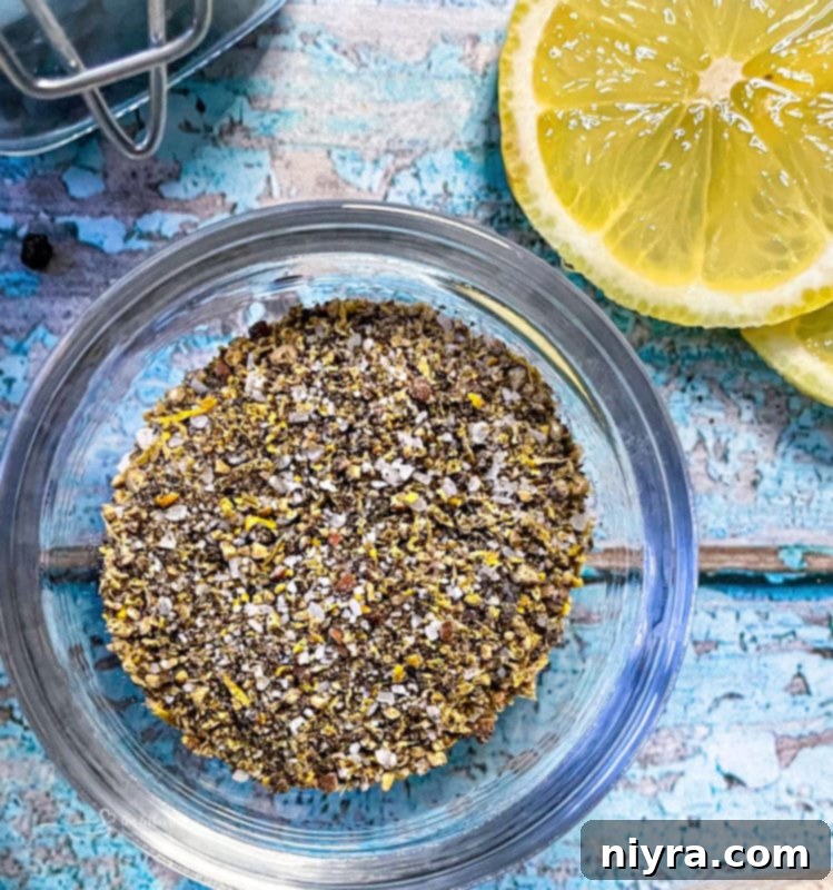 DIY Lemon Pepper Perfection 2 Homemade lemon pepper seasoning in a small bowl with fresh lemons and black peppercorns