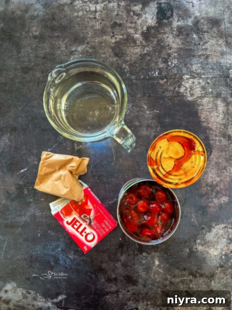 A serving of Cherry Pie Jell-O Salad in a small glass dish, garnished with a sprig of mint and fresh cherries.
