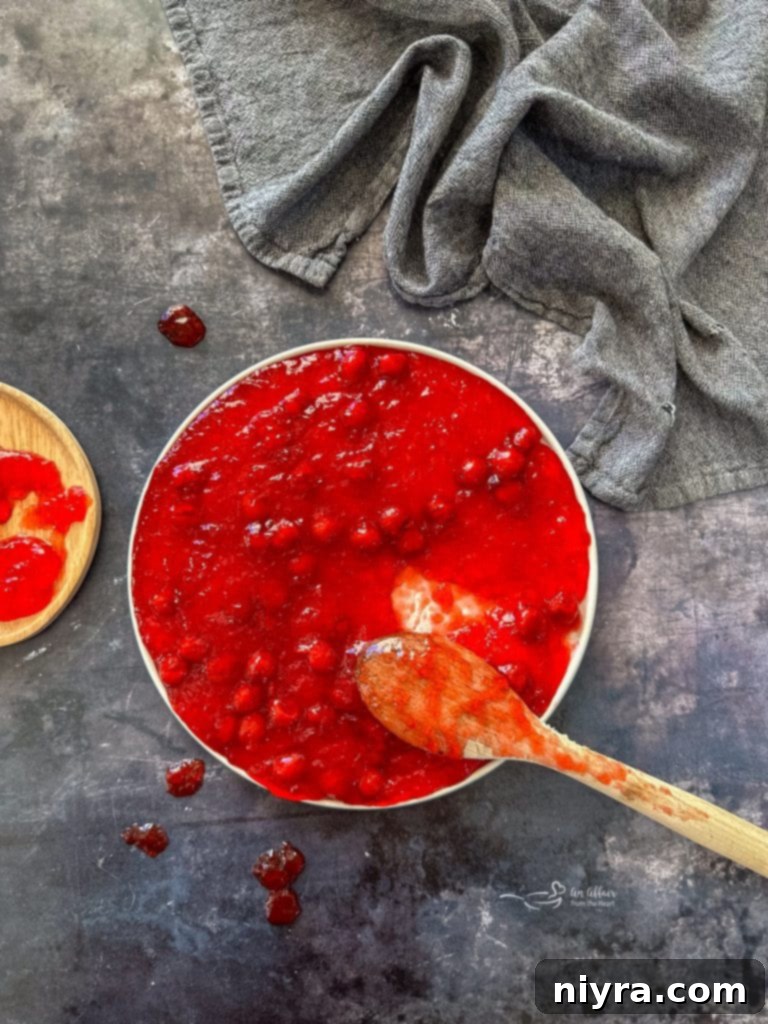 A close-up of the Cherry Pie Jell-O Salad showing the vibrant red color and whole cherry pieces.