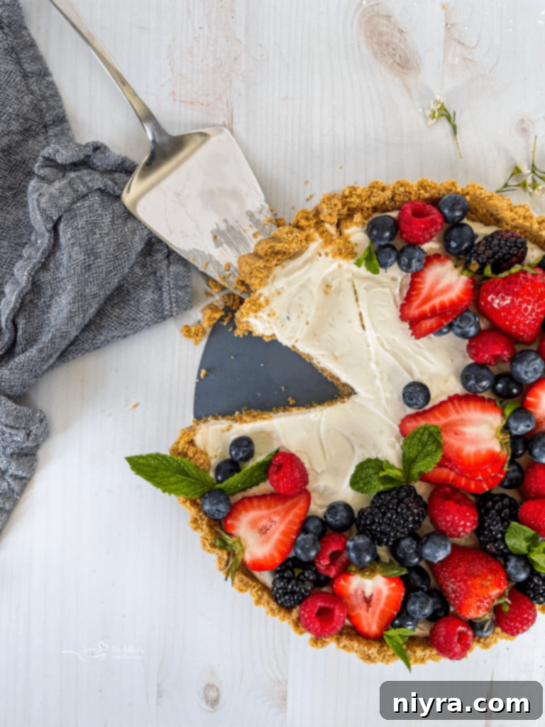 Top view of one no-bake fruit tart with fresh berries and mint, resembling a light and fruity dessert.