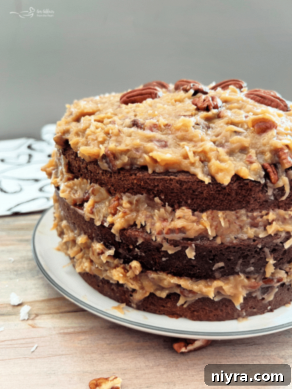 Classic Homemade German Chocolate Cake on a white plate with coconut pecan frosting, ready to be served.