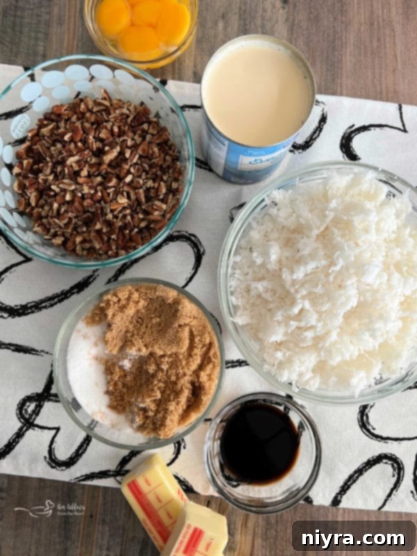 Key ingredients for homemade German Chocolate Cake frosting, including pecans, shredded coconut, brown sugar, white sugar, egg yolks, vanilla extract, butter, and evaporated milk, arranged on a surface.