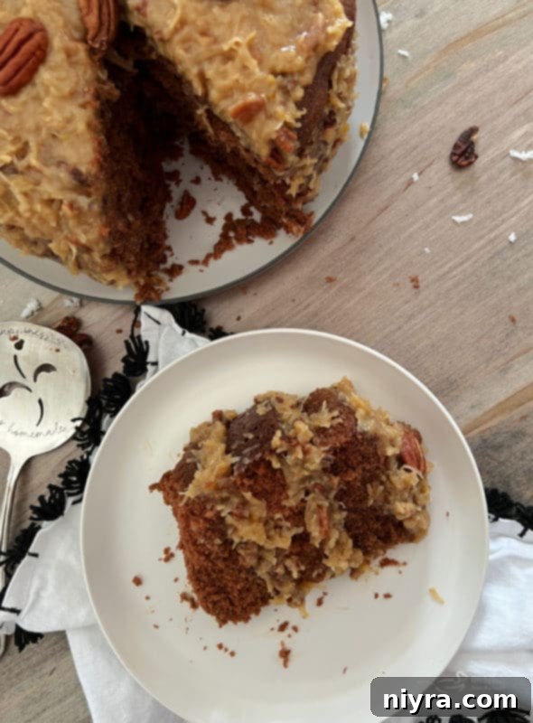 A perfectly sliced piece of German Chocolate Cake on a white plate, showcasing the distinct layers of rich chocolate cake and the signature coconut pecan frosting, ready to be enjoyed.