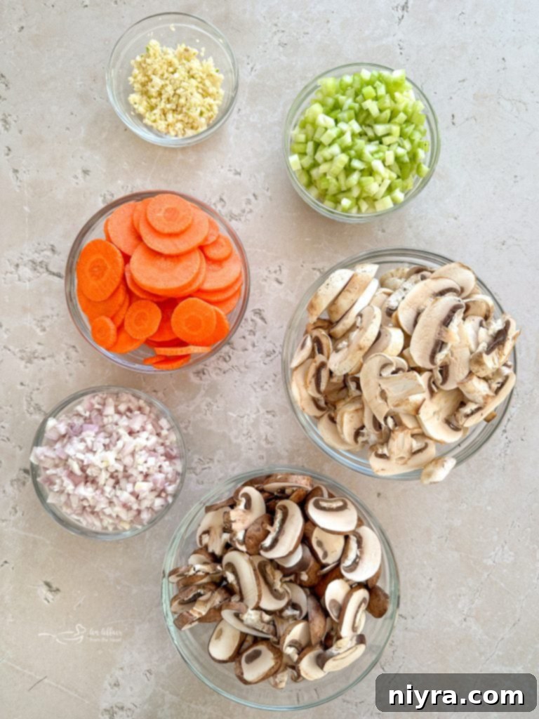 Ingredients laid out for Vegetable Beef Barley Soup with Mushrooms: beef, mushrooms, carrots, celery, and herbs.