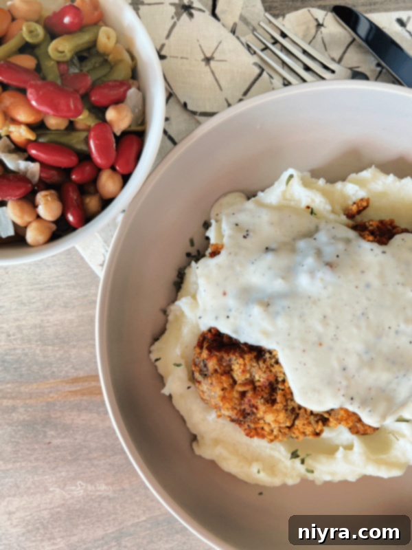Air Fryer Chicken Fried Steak served over creamy mashed potatoes, topped with white peppered gravy.