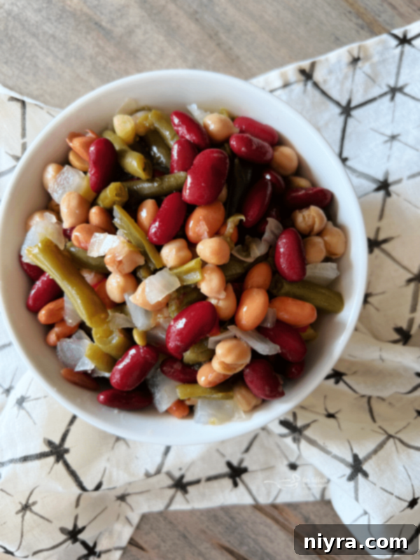 Paisley Farm Five Bean Salad in a bowl with serving utensils.