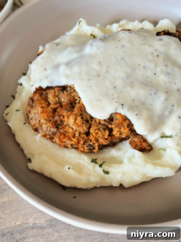 Close-up of golden brown Air Fryer Chicken Fried Steak with white gravy.
