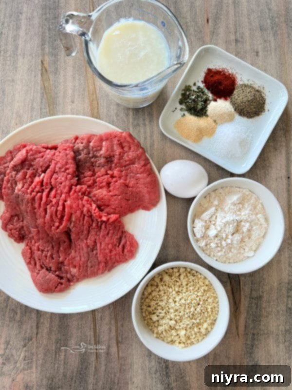 All the ingredients for Air Fryer Chicken Fried Steak laid out on a table: cube steaks, panko, flour, seasonings, egg, buttermilk, and butter, milk for gravy.