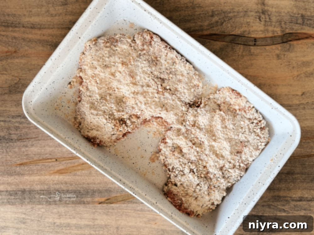 Two breaded cube steaks resting on a plate or baking sheet.