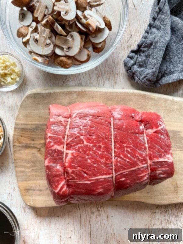 Top view of a raw beef chuck roast on a cutting board, ready for preparation to become tender French Dip meat.