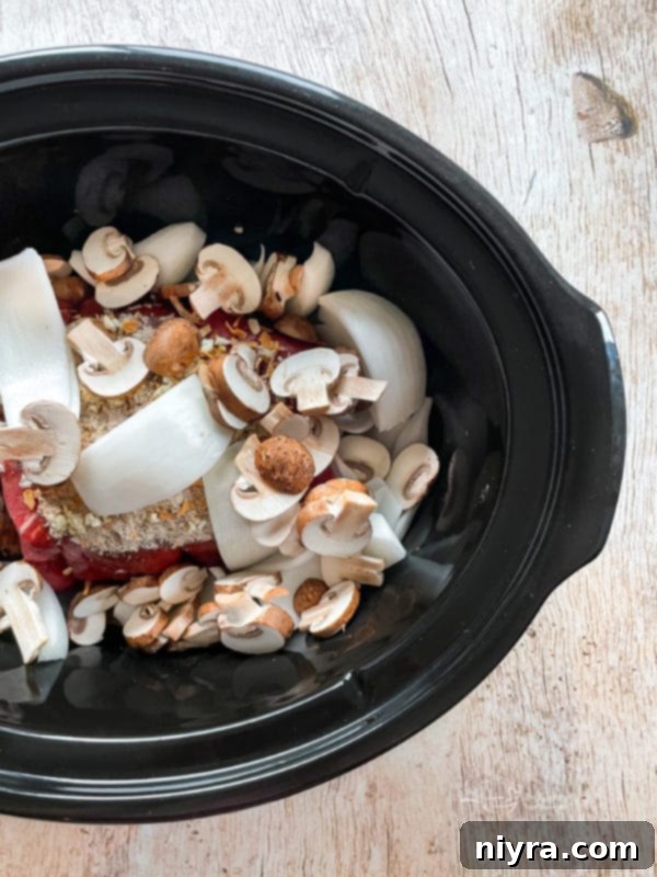 Ingredients for French Dip sandwiches placed inside a Crock Pot, ready for slow cooking.