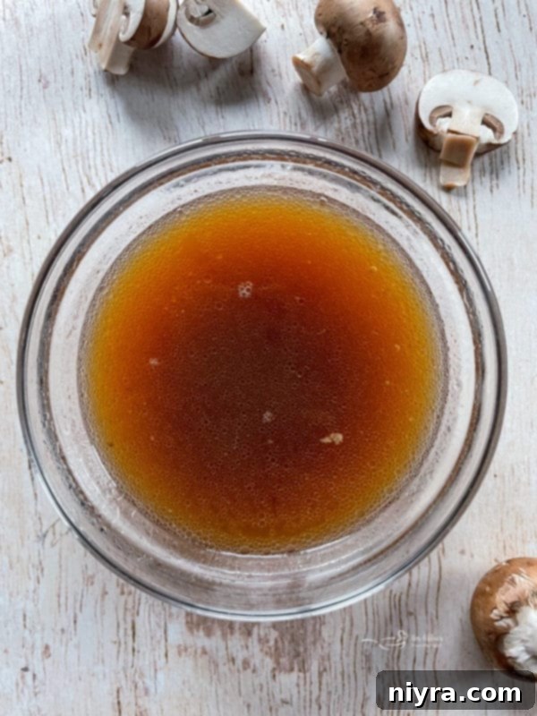 Rich, dark au jus broth in a bowl, perfect for dipping French Dip sandwiches.