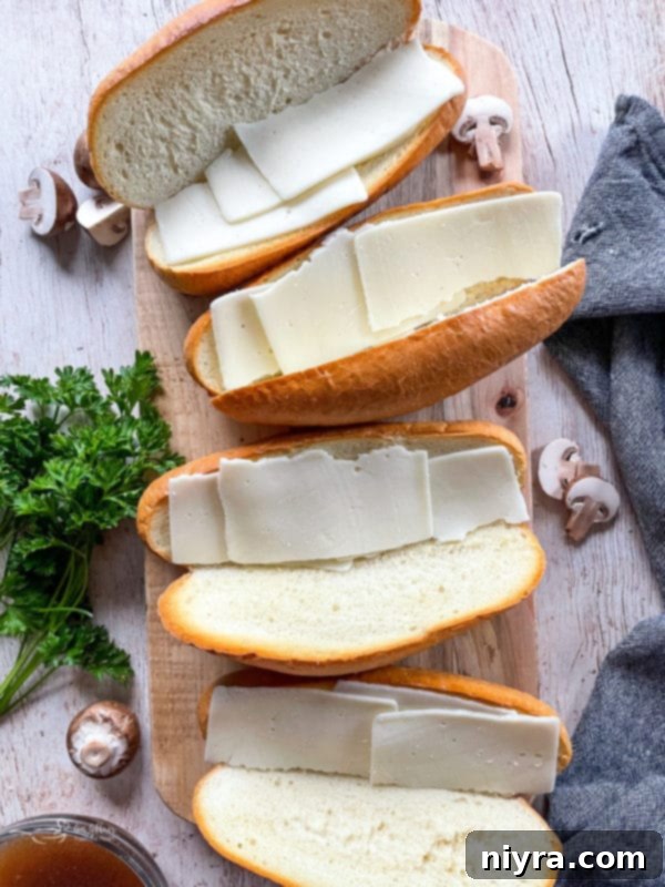 Toasted hoagie rolls with melted provolone cheese, prepared for the addition of shredded beef for French Dip sandwiches.