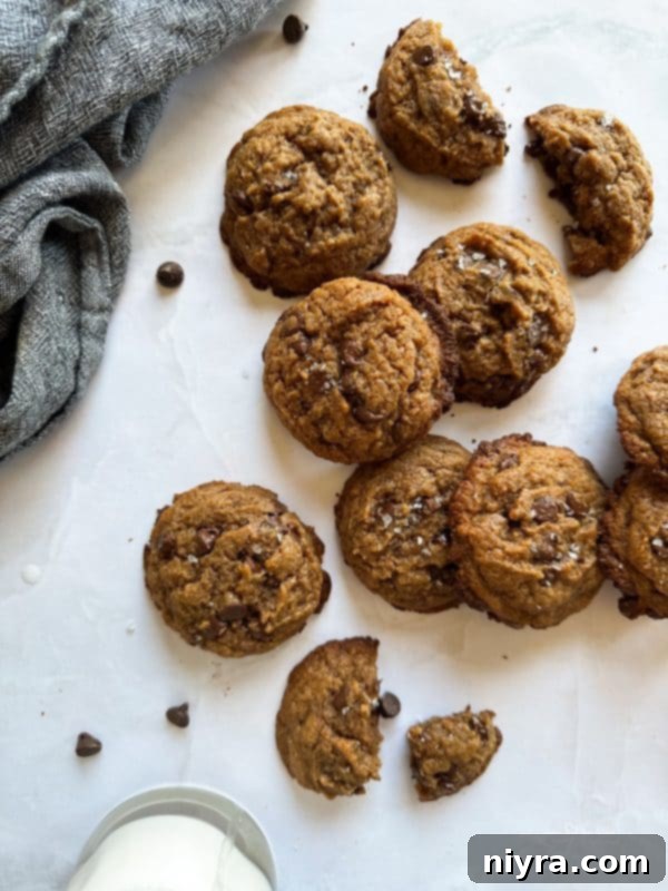 Close-up of three Malted Chocolate Chip Cookies stacked on a wooden surface, showing their chewy texture